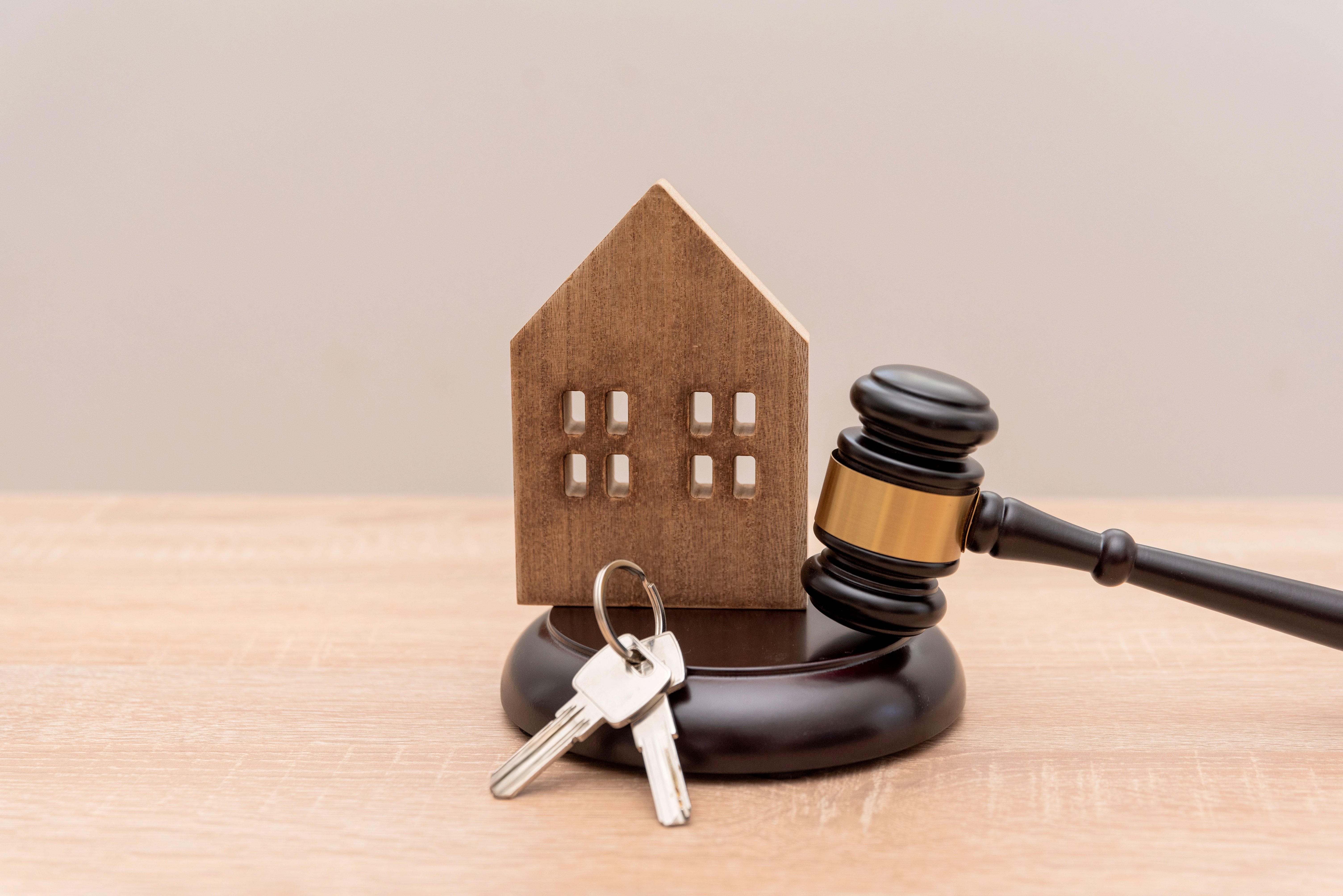 A model house and keys next to a gavel.